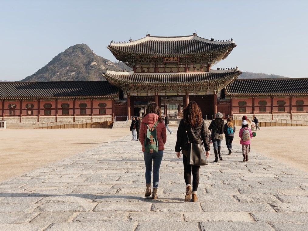Greenheart Seoul Two women walk toward an ornate building in Seoul, South Korea.